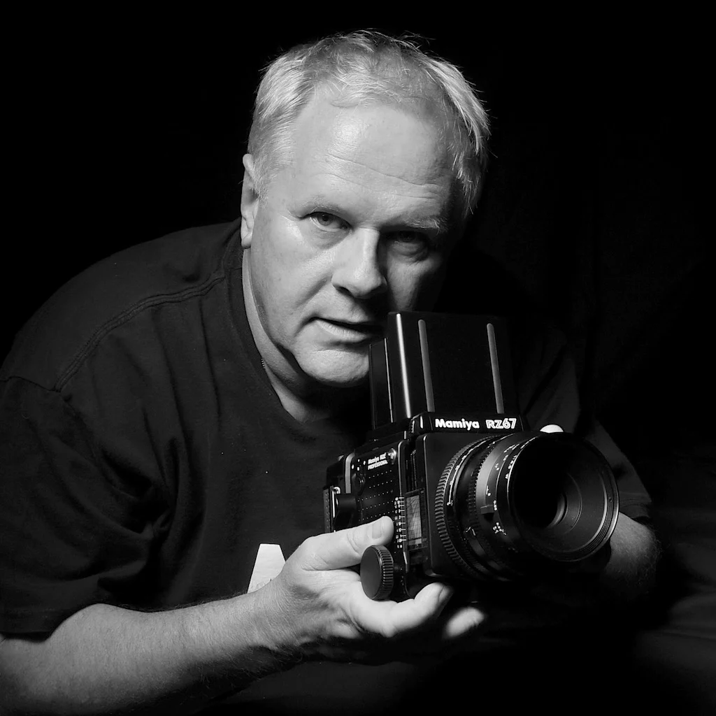 Peter Pickering, photographer, holding a Mamiya medium format camera and taking a picture